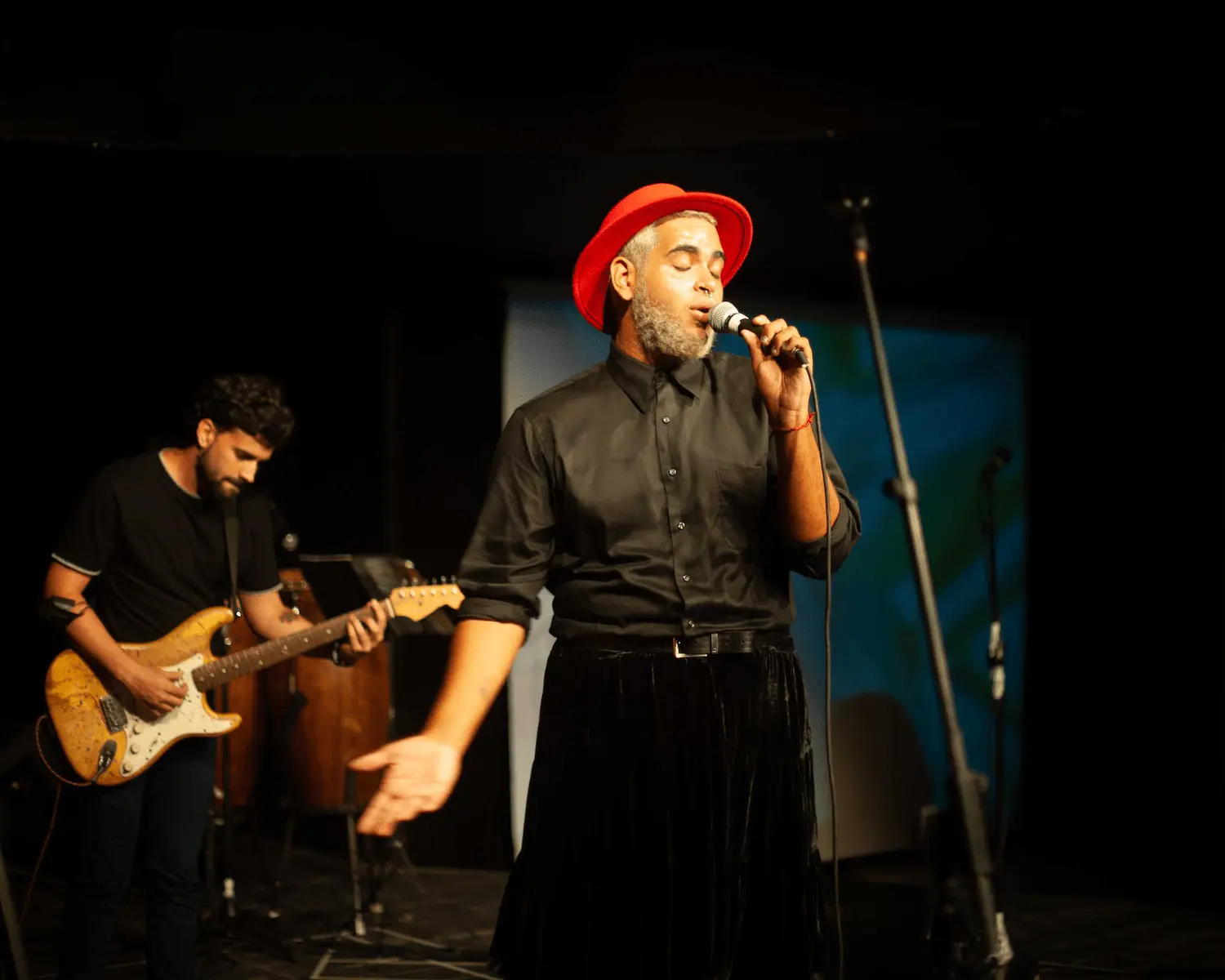 sergio ochoa con un sombrero rojo cantnado en el teatro bertolt brecht
