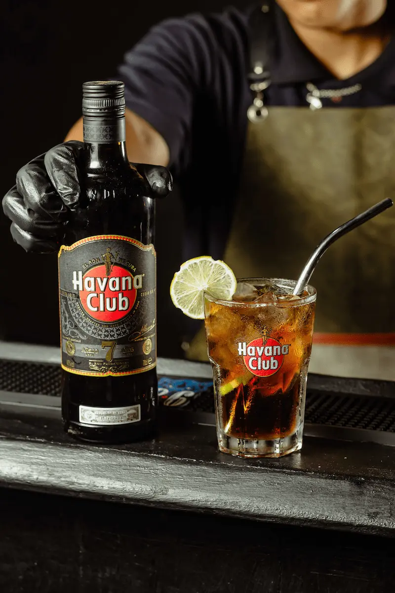 bartender agarando botella de Ron havana club junto a un trago