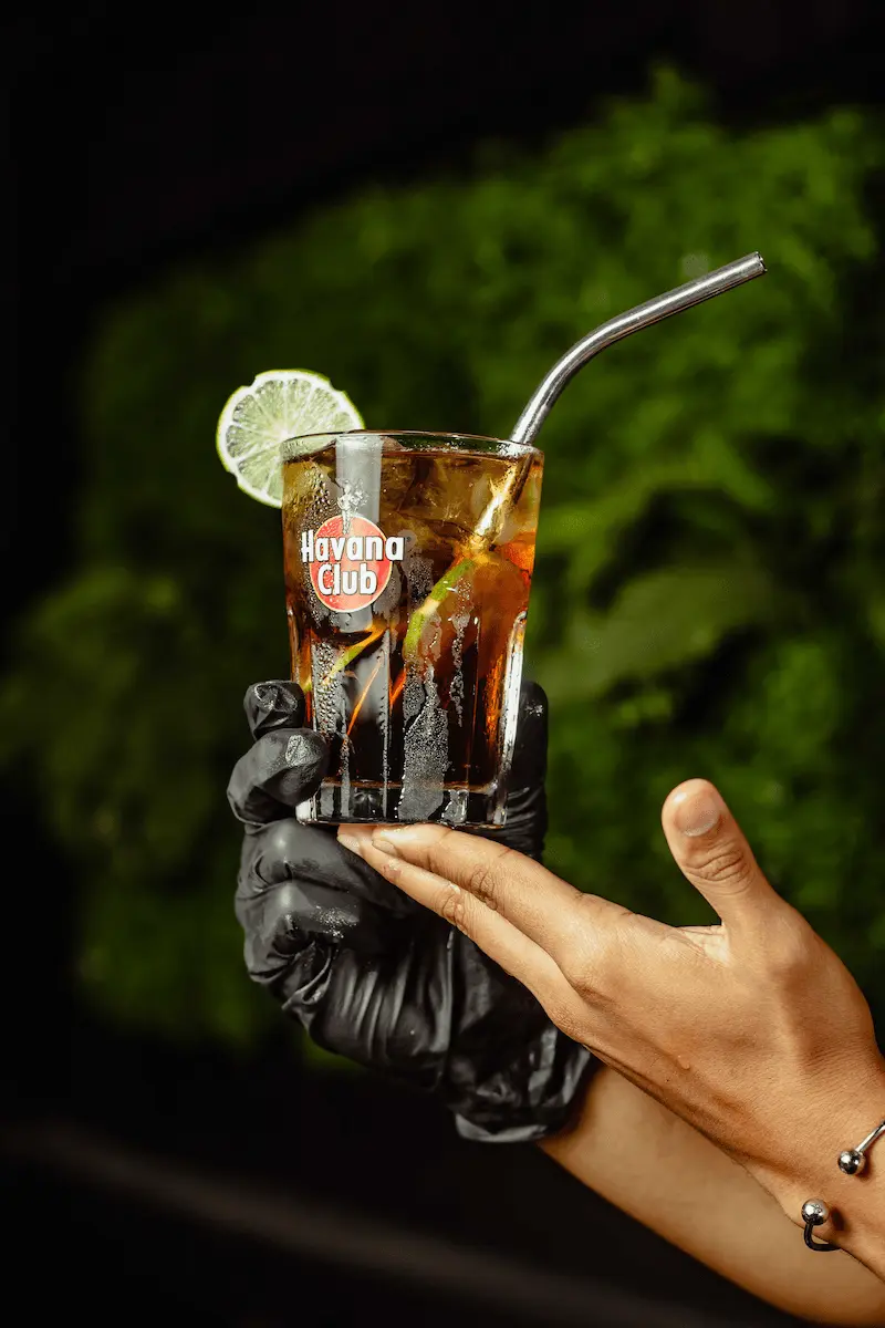 manos sosteniendo trago roncola en vaso de havana club
